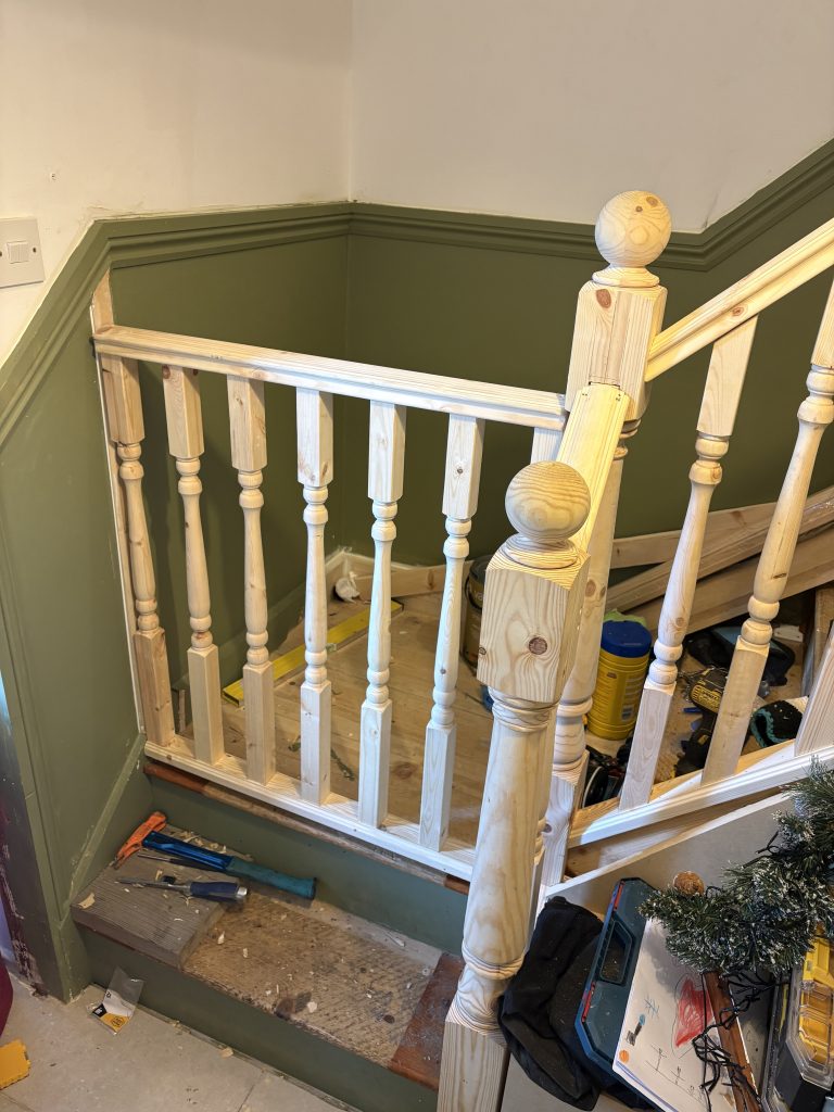 An image of the bottom of a staircase that has had a child gate built into it using the same handrail and spindles as the ones on the stairs. Keeping the stair gate in the style of the stairs.
